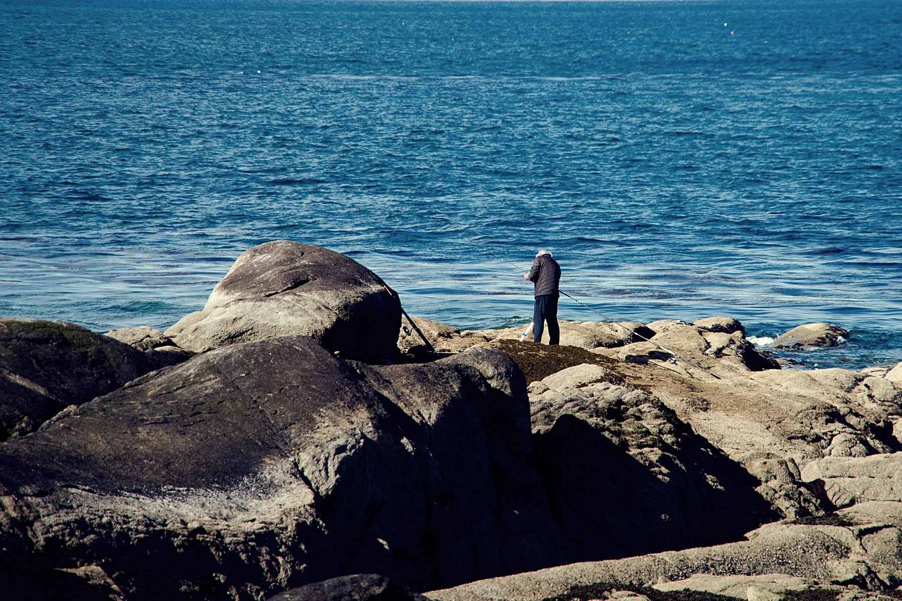 An angler standing on rugged coastal rocks