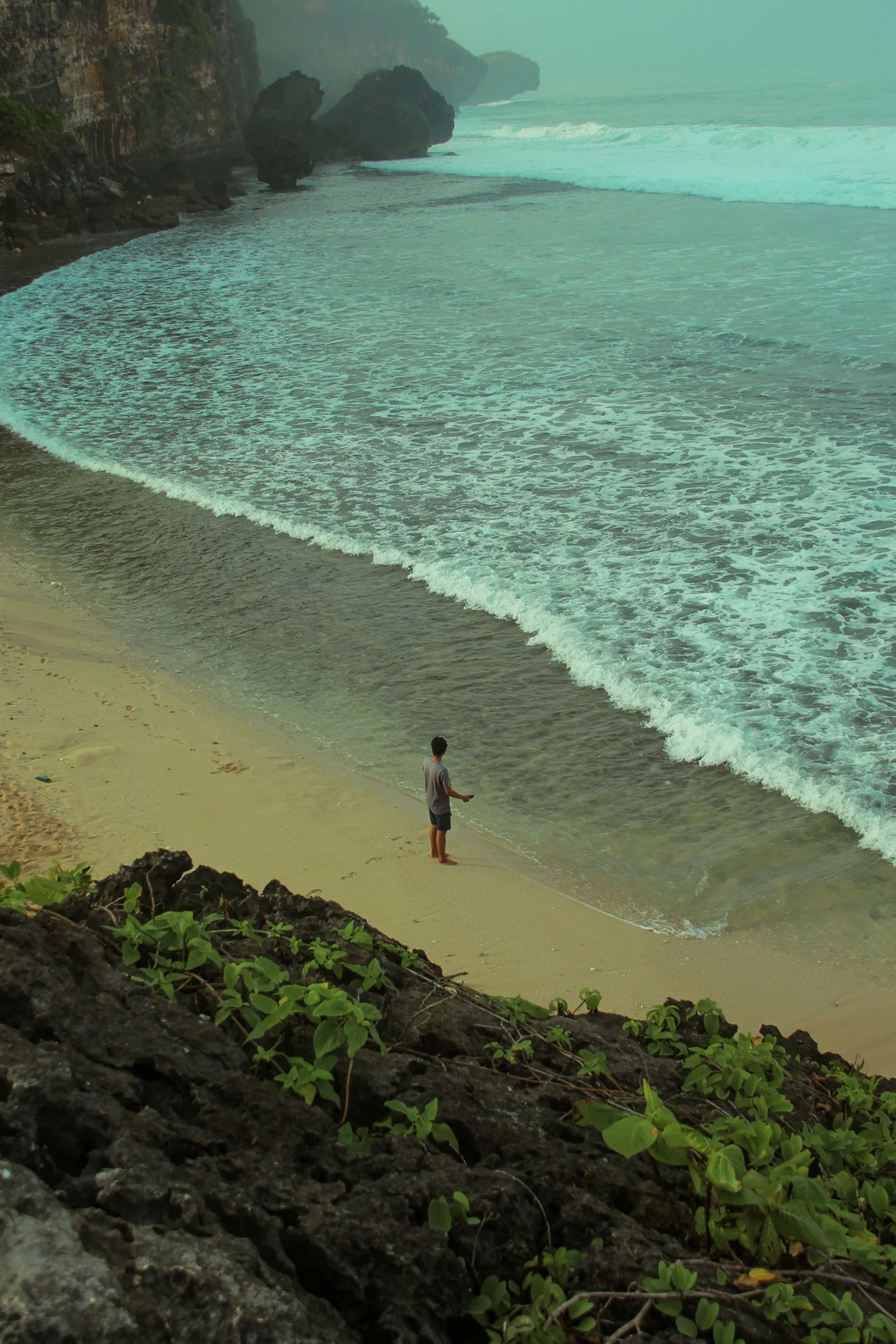 A solitary angler viewed above a rocky beach